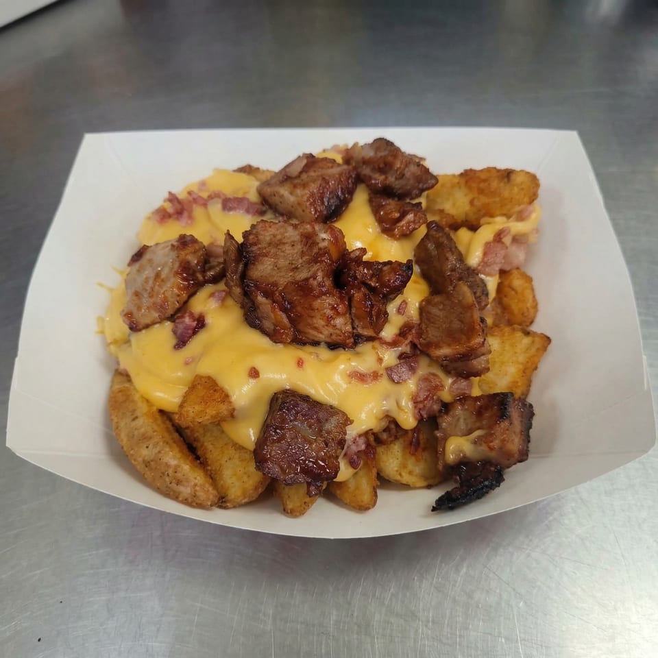 Loaded fries from The Clarksville Crust, topped with melted cheese, bacon bits, and chunks of meat.