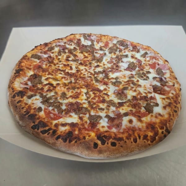 A freshly baked Clarksville Crust pizza, loaded with meat toppings and melted cheese.