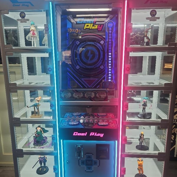 A brightly lit arcade game with anime figures displayed in glass cases on either side.