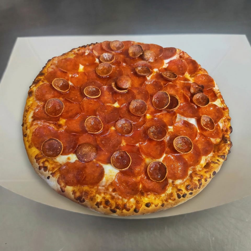 A freshly baked pepperoni pizza from The Clarksville Crust, with curled pepperoni cups and a golden crust.